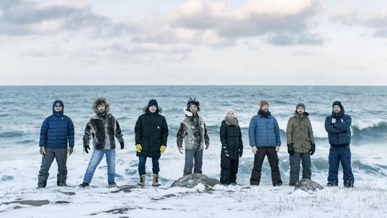 Members of Pamyua stand side by side in their winter clothes on a snowy beach